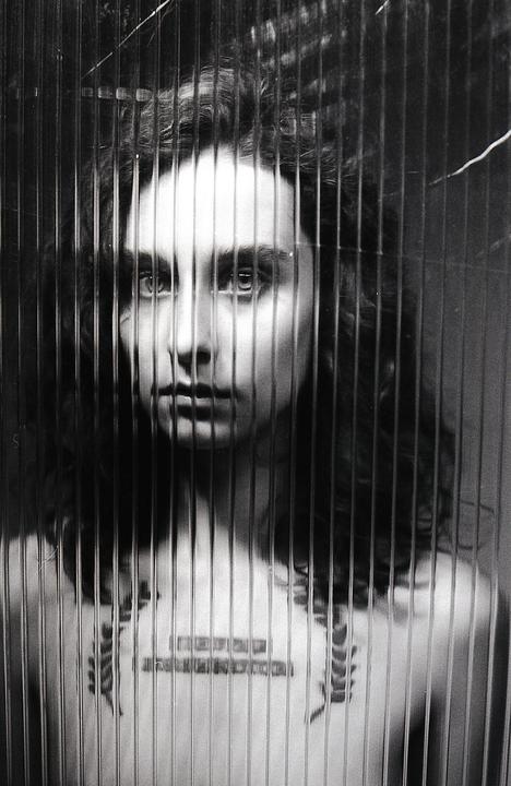A woman with long hair is visible through a textured glass surface.