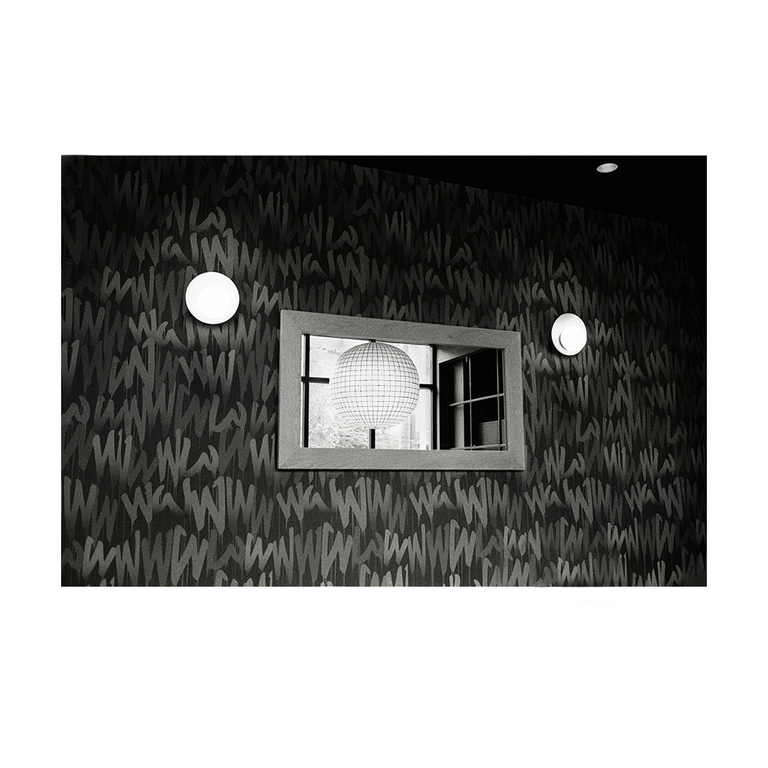 A disco ball is reflected in a mirror on a wall with a graffiti pattern.