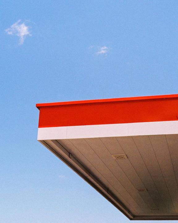 The red and white roof of a building is visible against a clear blue sky with a few small clouds.