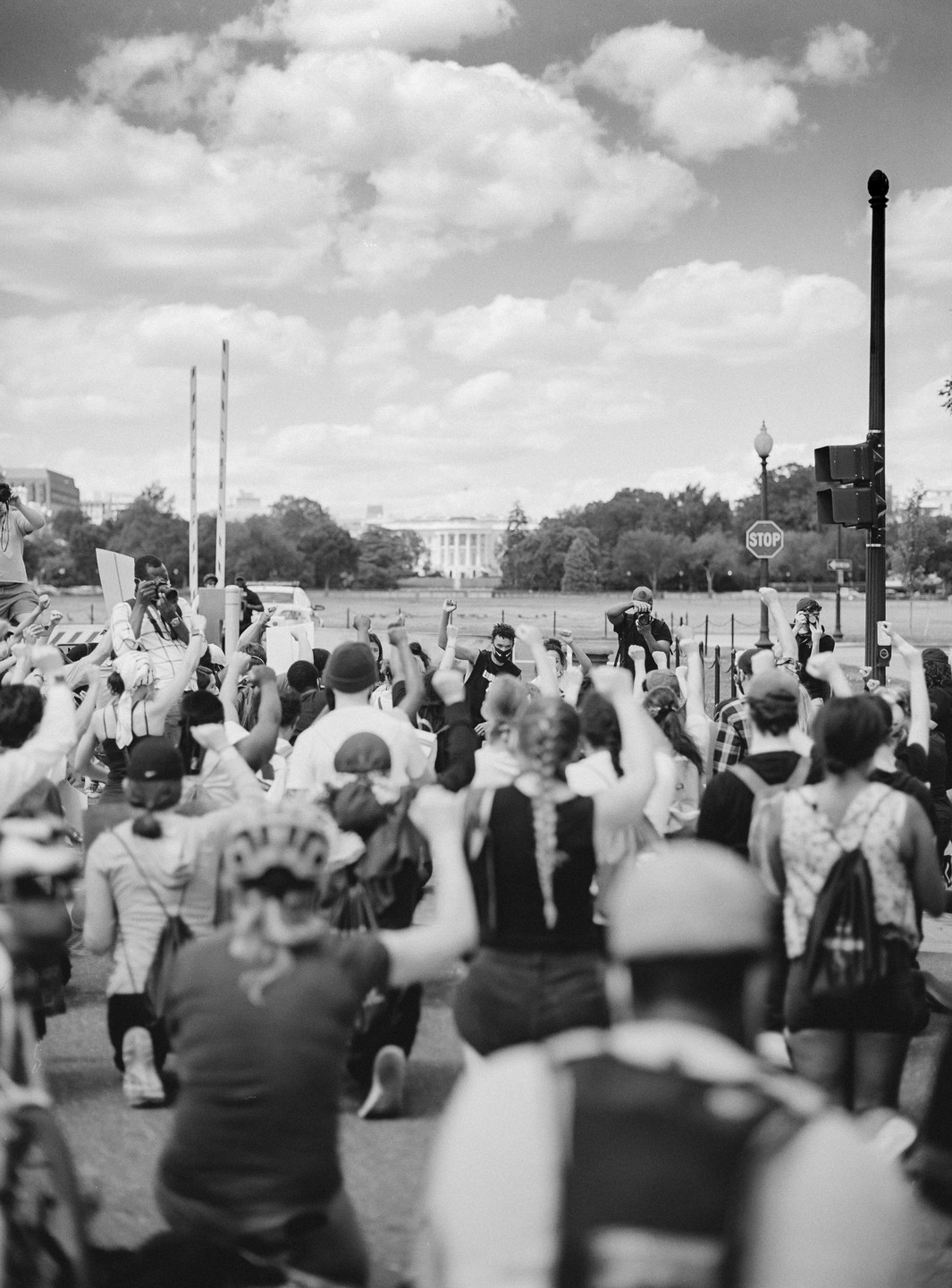A crowd of people with raised fists are protesting in front of the White House.