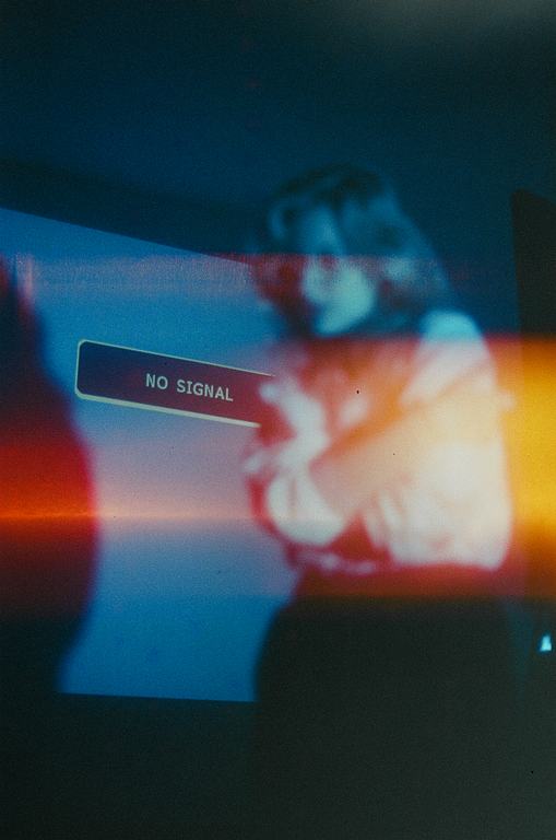 A "NO SIGNAL" message is displayed on a screen with a blurry figure in the background.