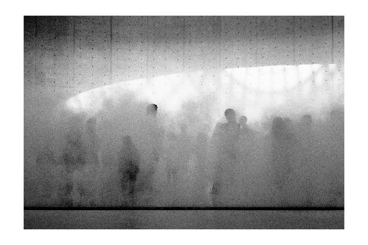 A group of people are obscured by a cloud of mist in a black and white photograph.