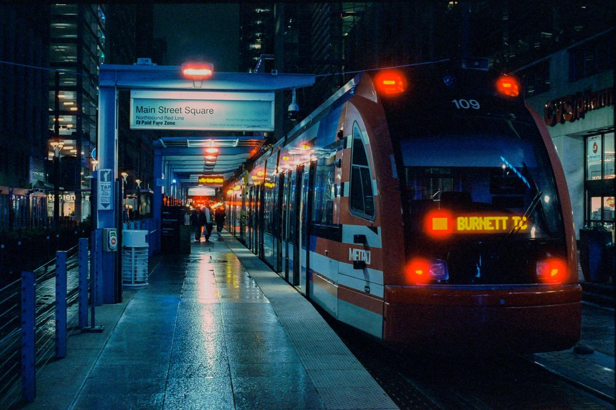 A red and white train is stopped at a station platform at night.