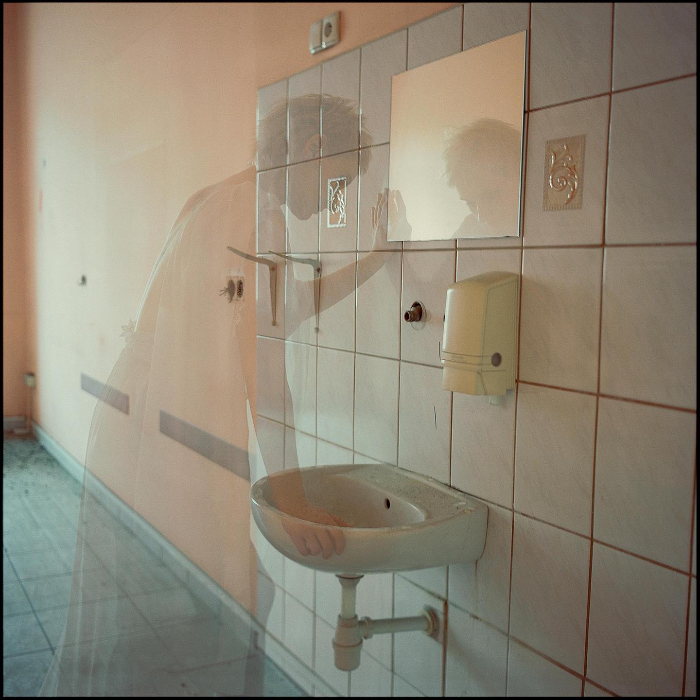 A double exposure shows a woman in a wedding dress in a tiled bathroom with a sink and mirror.