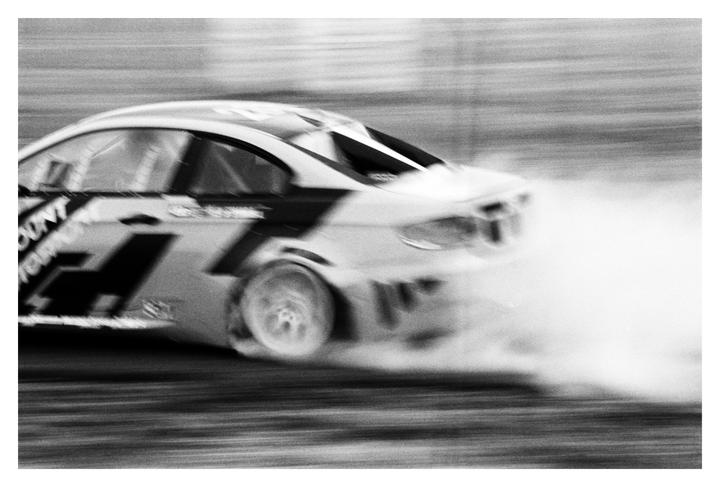 A racing car drifts, creating a large cloud of smoke behind its tires.