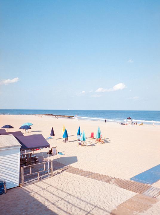 A sandy beach with colorful umbrellas and chairs under a clear blue sky.