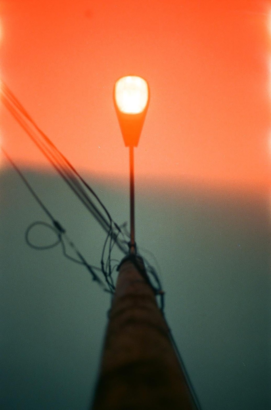 A street light glows brightly against a gradient sky of orange and blue.