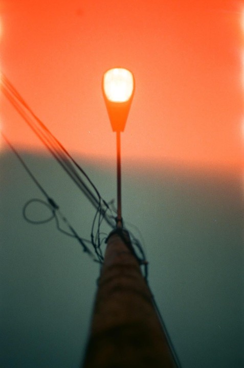 A street light glows brightly against a gradient sky of orange and blue.