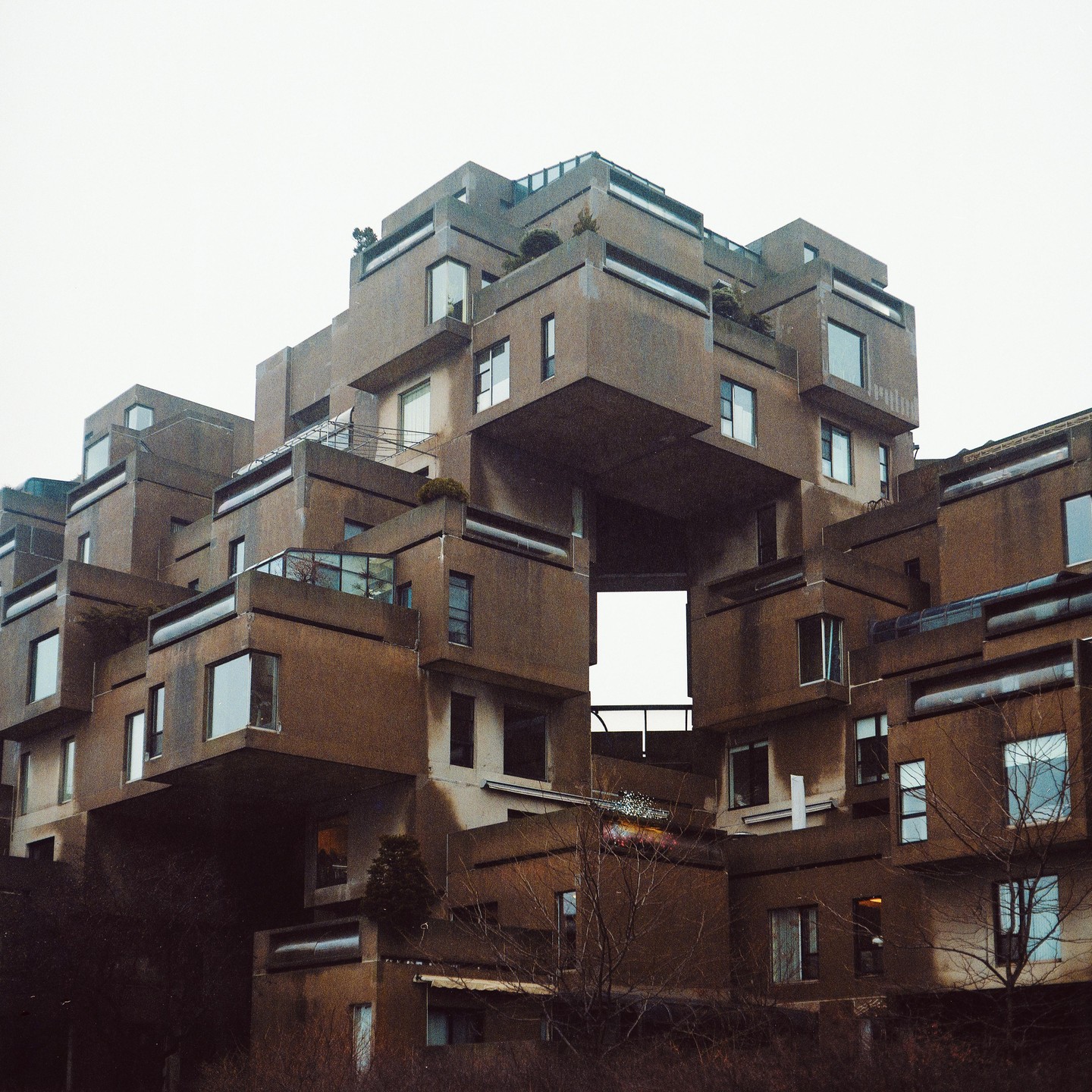A brutalist apartment complex with many windows and balconies is visible from a low angle.
