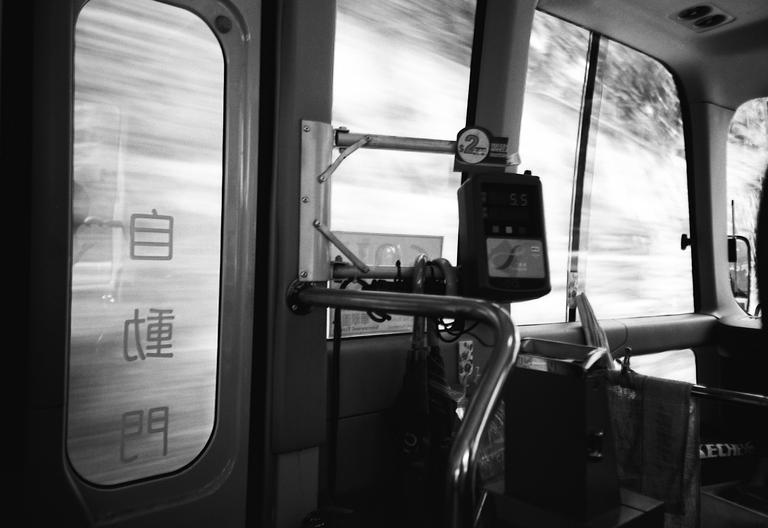 The interior of a moving bus is visible, with a payment machine and a door with Chinese characters.