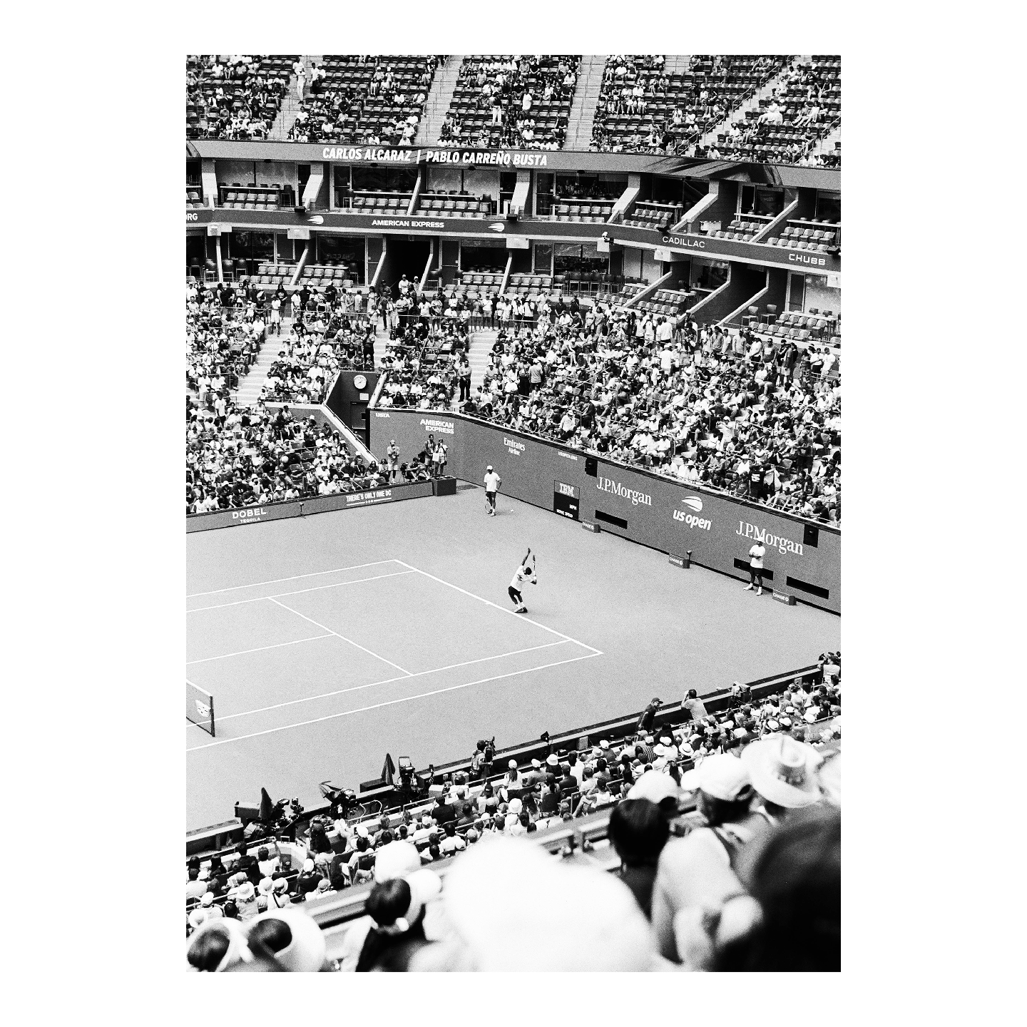 A tennis match is underway on a court surrounded by spectators in a large stadium.