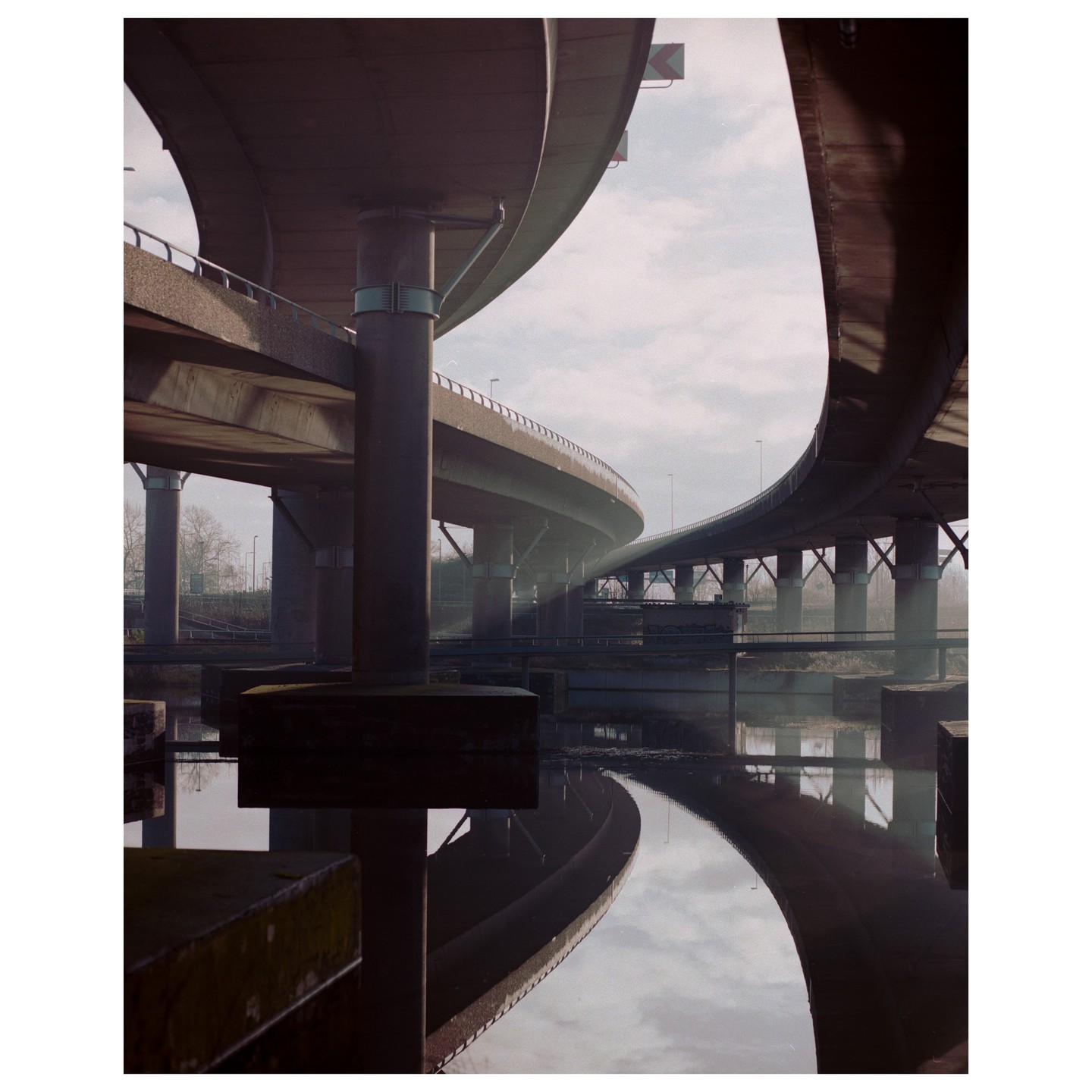 A complex highway interchange with multiple elevated roads is reflected in the water below.