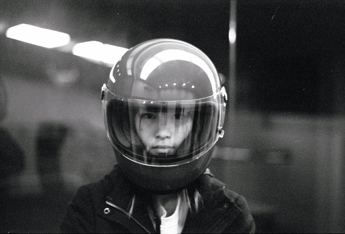 A person wearing a motorcycle helmet with a clear visor looks directly at the viewer.