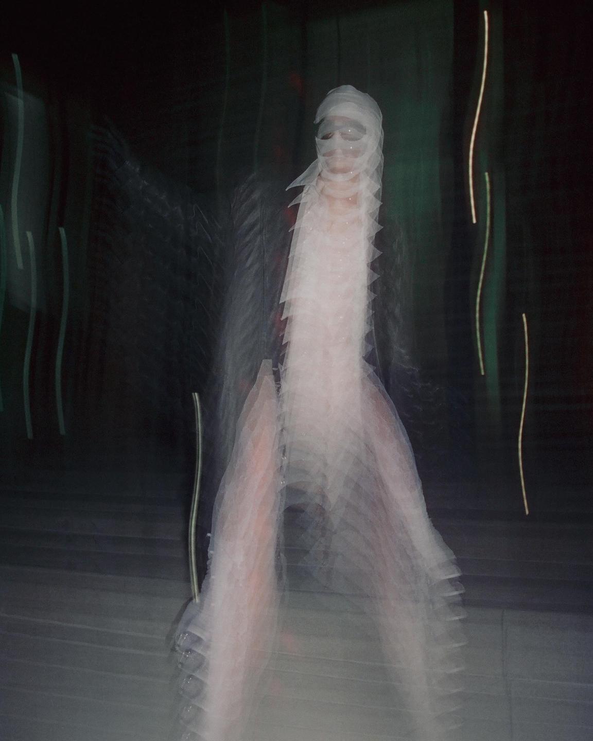 A person with a bandaged head and face is captured in a blurry, streaked long exposure.