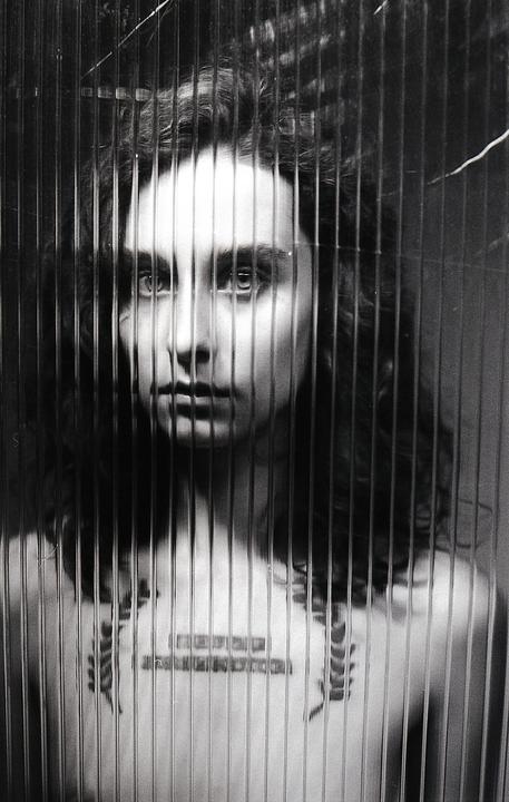 A woman with long hair is visible through a textured glass panel.