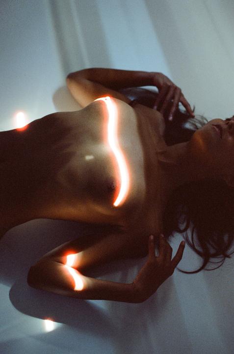 A woman lies on a surface with glowing orange light strips across her body.