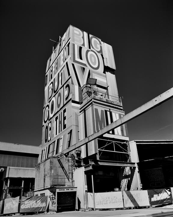A tall building with large letters spelling "BIG LOVE" and other words is shown from a low angle.