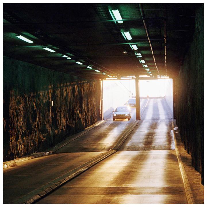 A car exits a dark tunnel into bright sunlight.