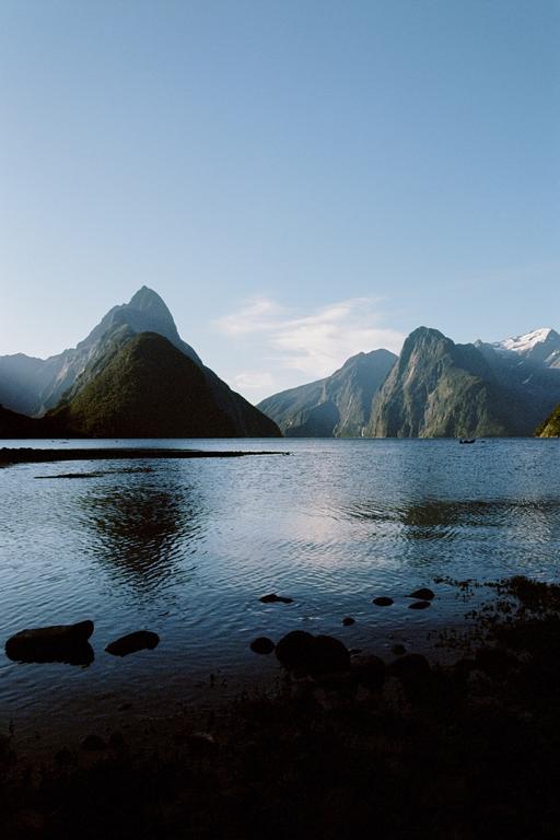 A body of water is surrounded by mountains under a clear sky.