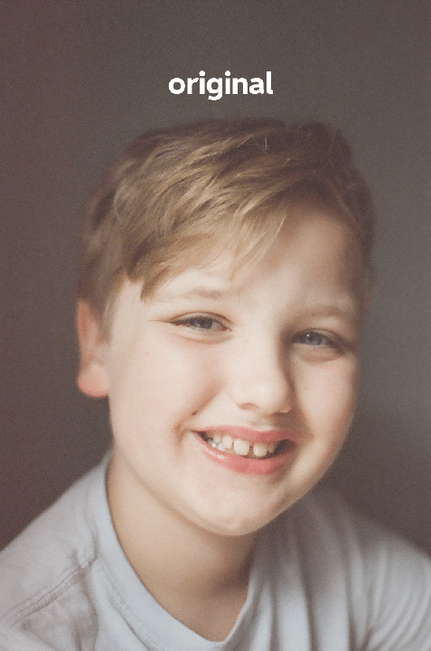 A young boy with blond hair and blue eyes smiles at the viewer.