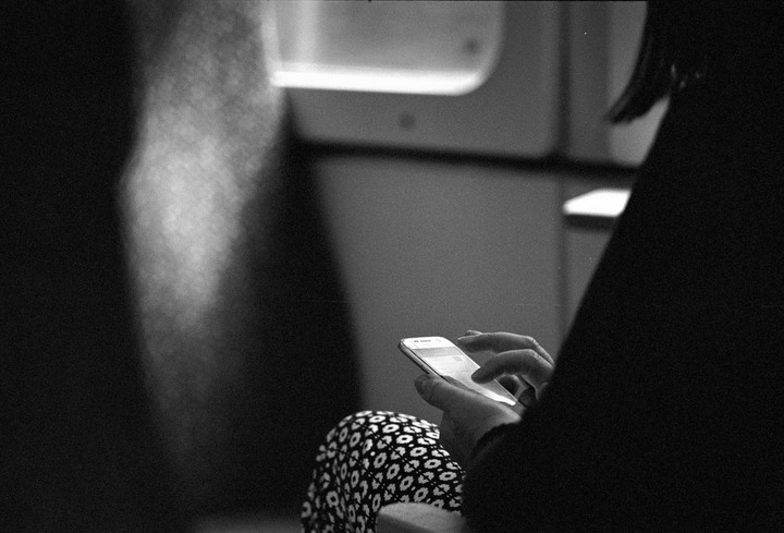A person is holding a smartphone and wearing patterned pants.