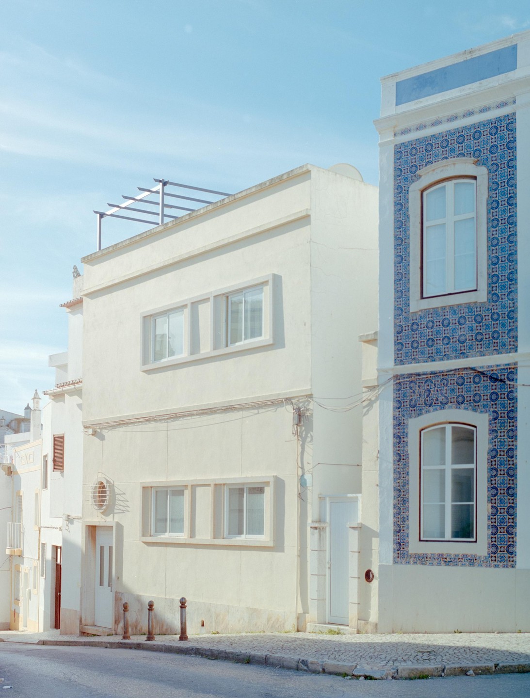 A street corner is lined with buildings, one of which is adorned with blue and white azulejo tiles.