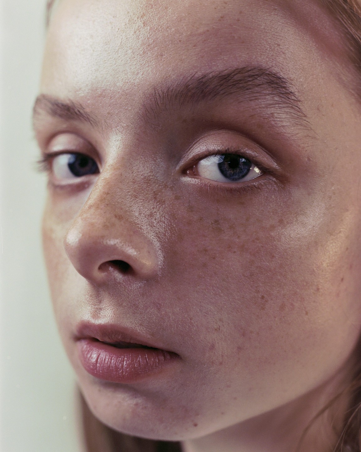 A woman with freckles and blue eyes looks directly at the viewer.