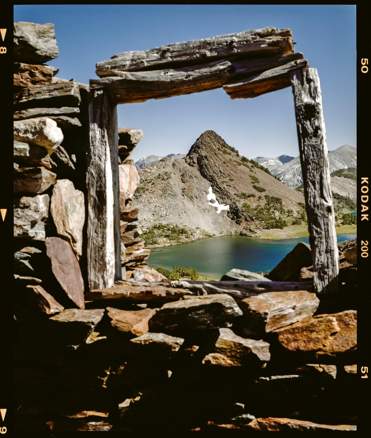 A mountain lake is visible through a window frame made of wood and stone.