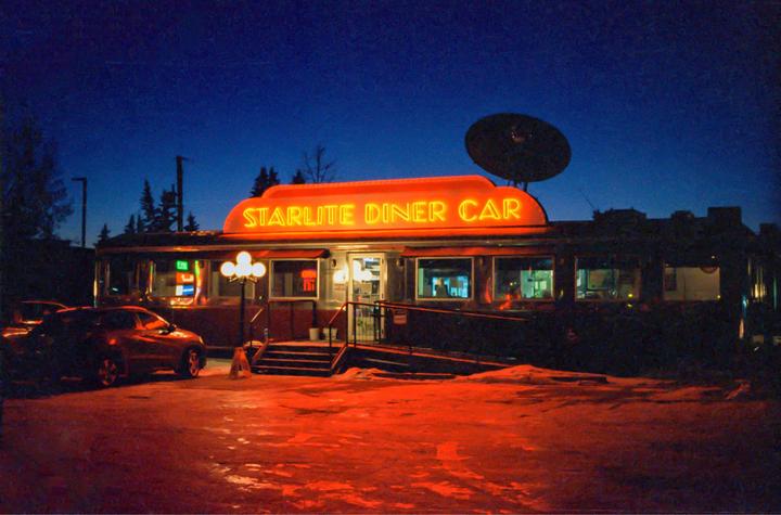 A diner with a neon sign that reads "Starlite Diner Car" is illuminated at night, with a car parked in front.