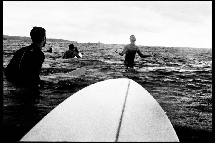 A group of surfers in wetsuits are in the ocean with their surfboards.