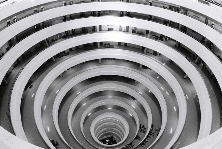 A high-angle view shows the interior of a building with circular balconies and a central open space.