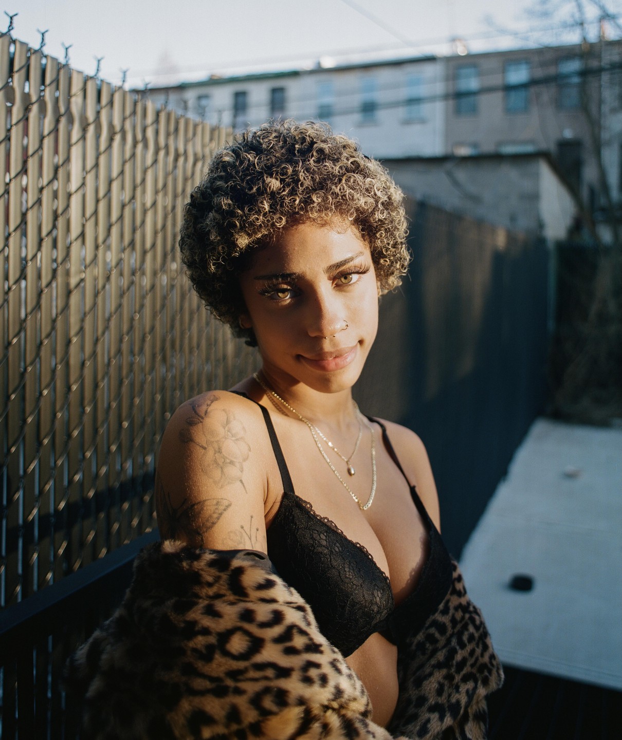 A woman with curly hair and a leopard print coat looks at the viewer.