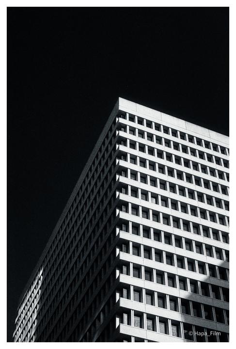 A tall building with many windows is photographed from a low angle against a dark sky.