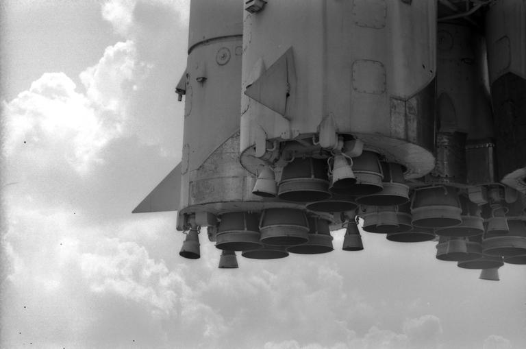 A large rocket with multiple engines is shown against a cloudy sky.