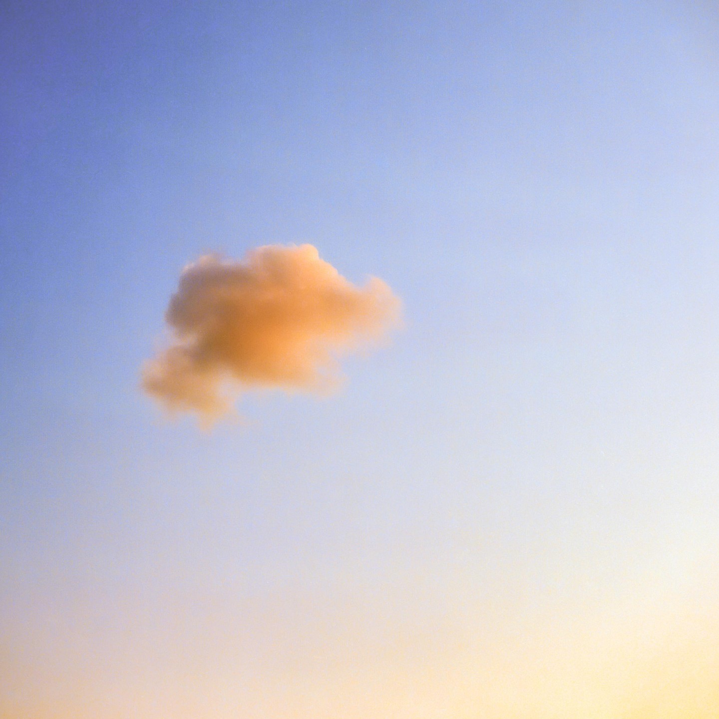 A single orange cloud floats in a blue and yellow sky.