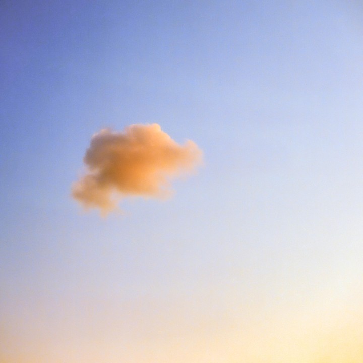 A single orange cloud floats in a blue and yellow sky.