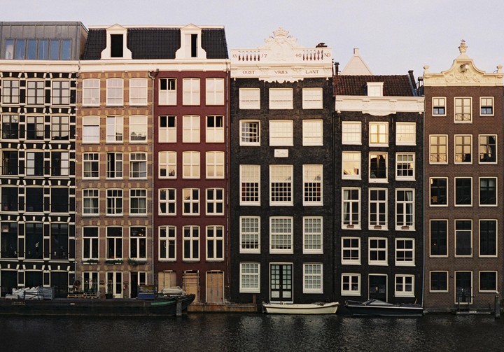 A row of colorful canal houses with boats docked in front of them.