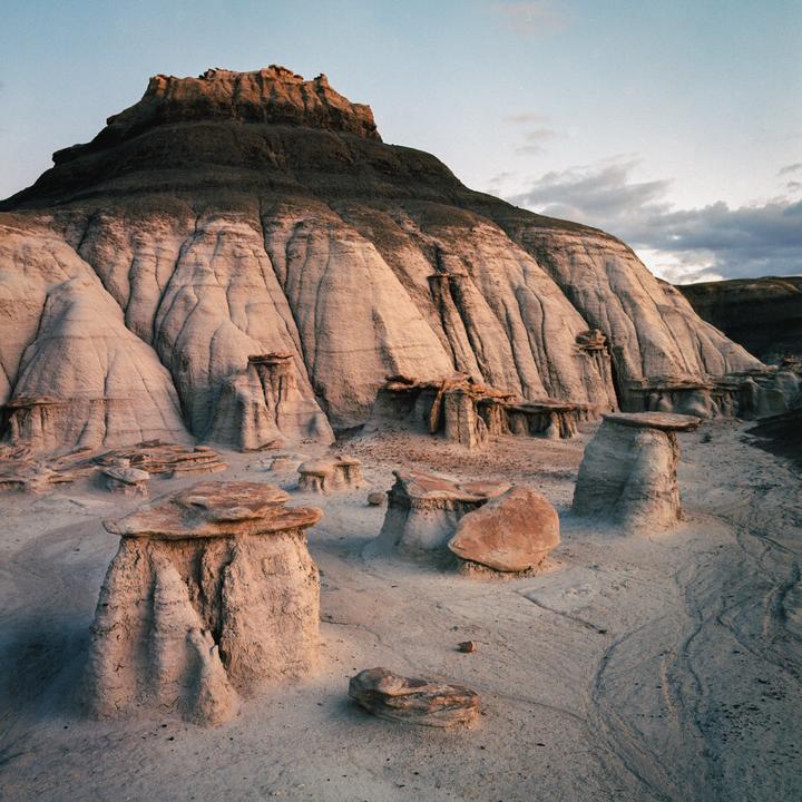 A large, dark mountain rises above a desert landscape with many small hoodoos in the foreground.