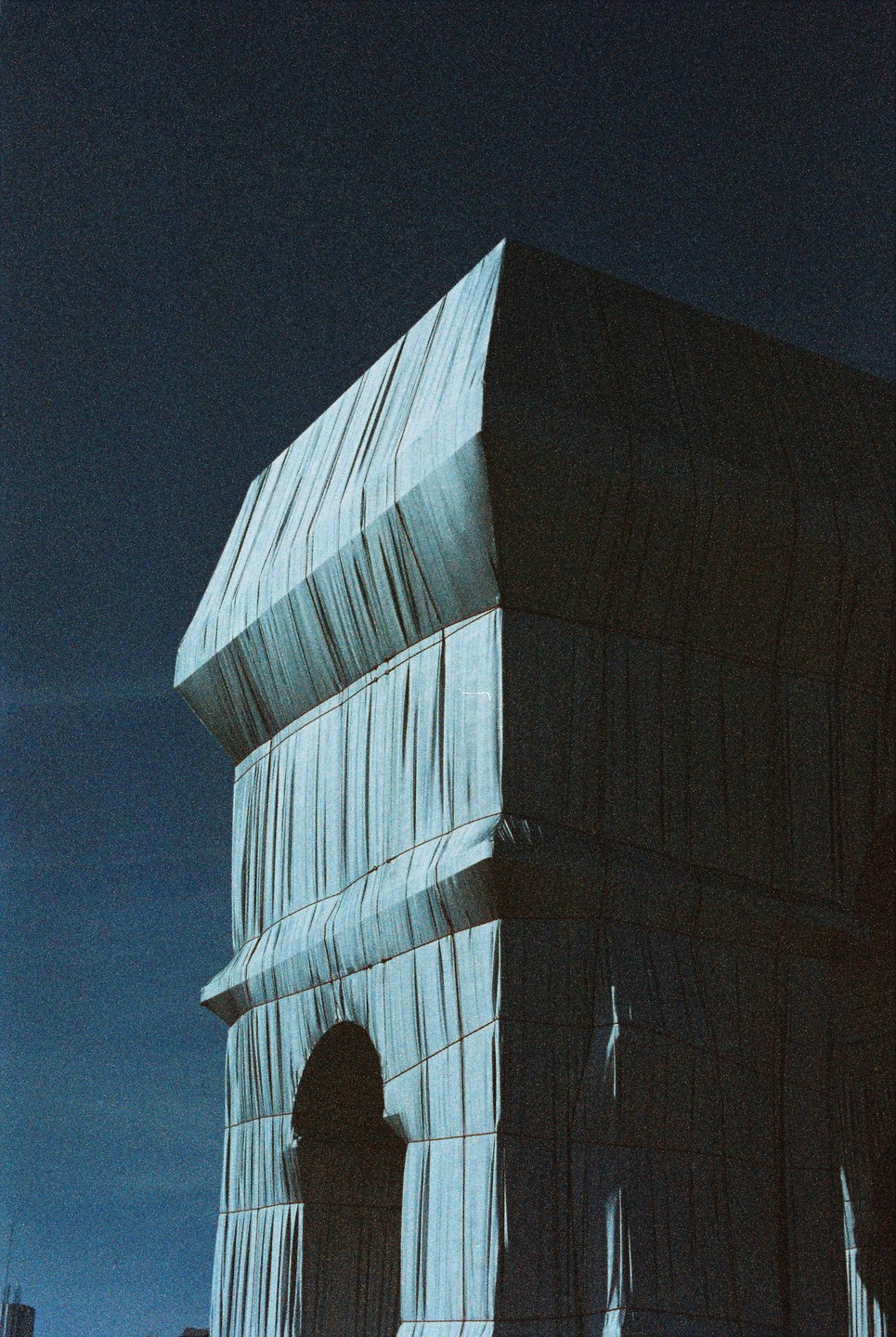 A large building wrapped in fabric stands against a dark sky.