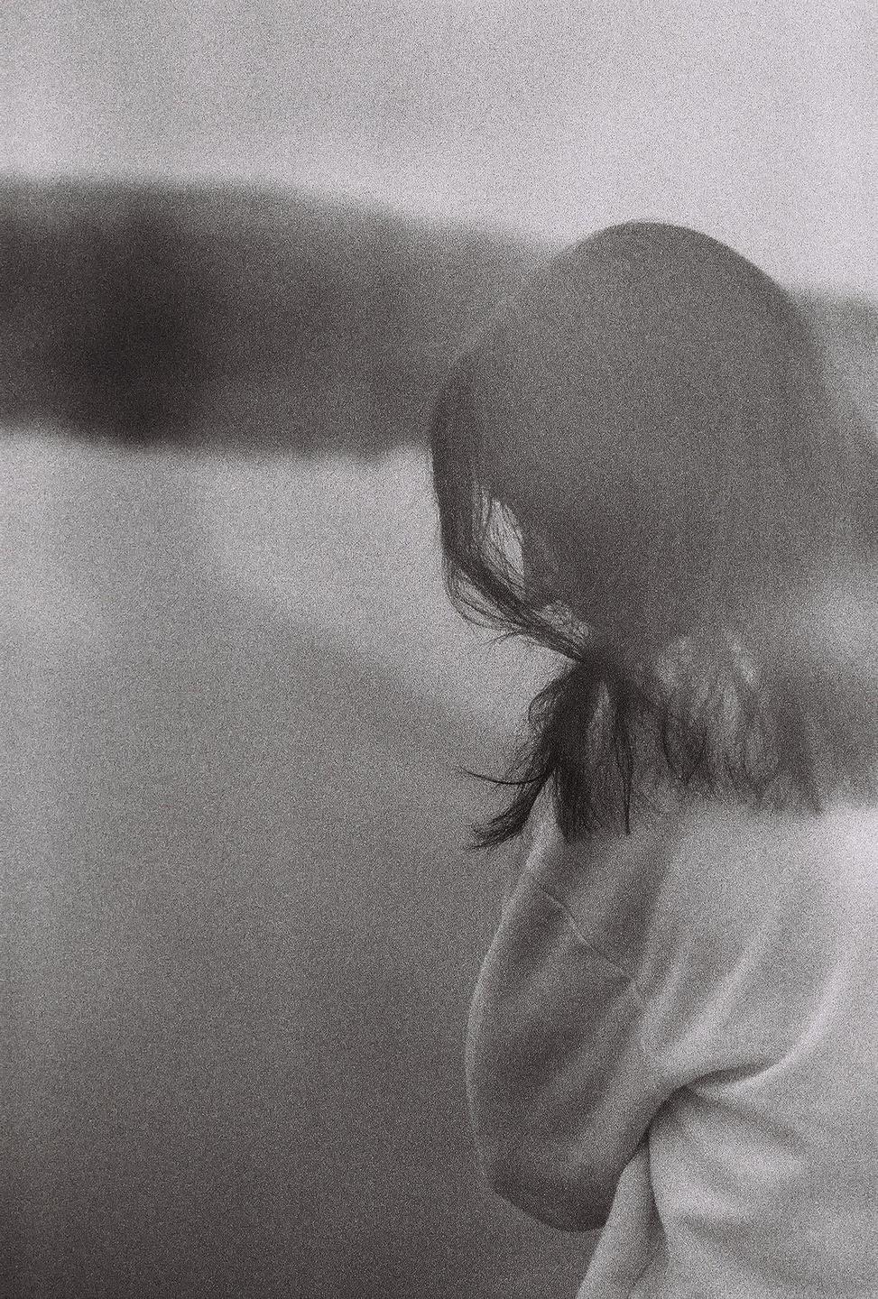 A woman with dark hair is seen from behind, looking away from the camera.