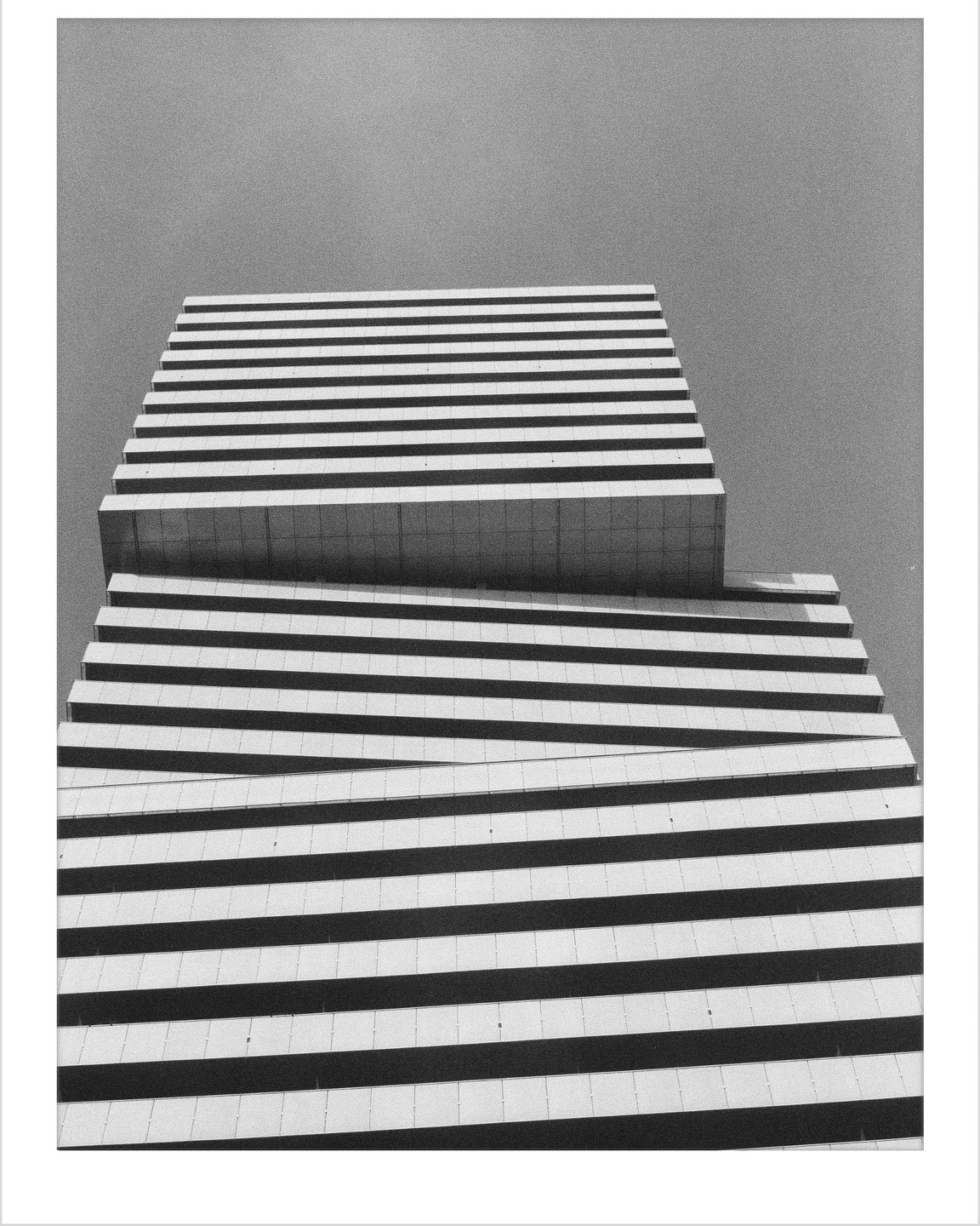 A low-angle view shows the geometric facade of a modern building with horizontal lines and shadows.