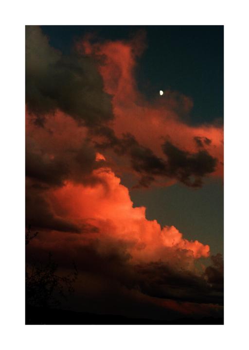 The moon is visible in a dark sky above red and dark clouds.