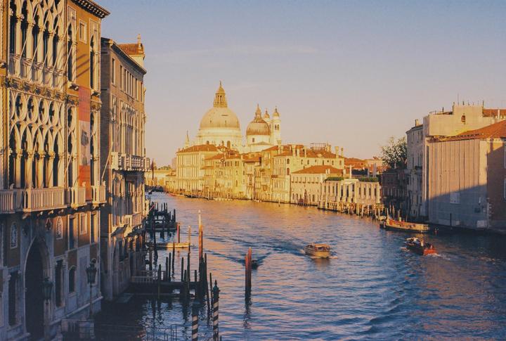 A canal in Venice is lined with historic buildings and two boats move through the water.