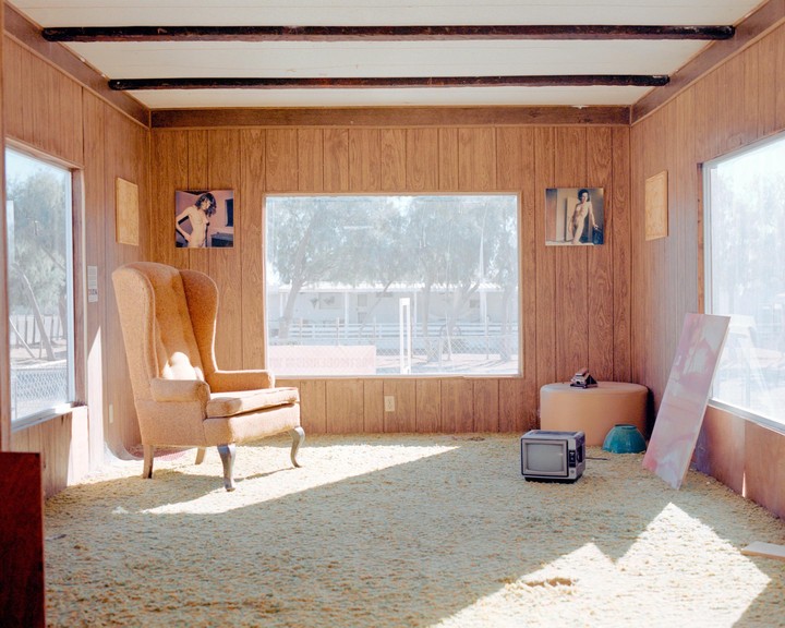 Sunlight streams into a room with wood paneling, a large armchair, and a small television.