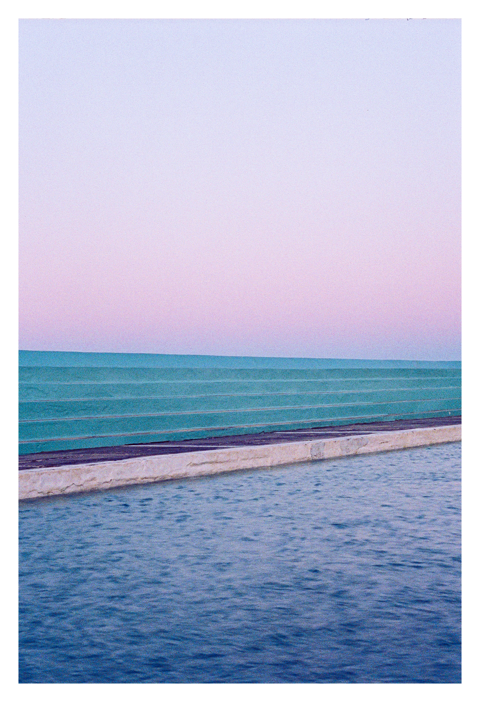 A swimming pool with turquoise walls is shown under a pink and purple sky.