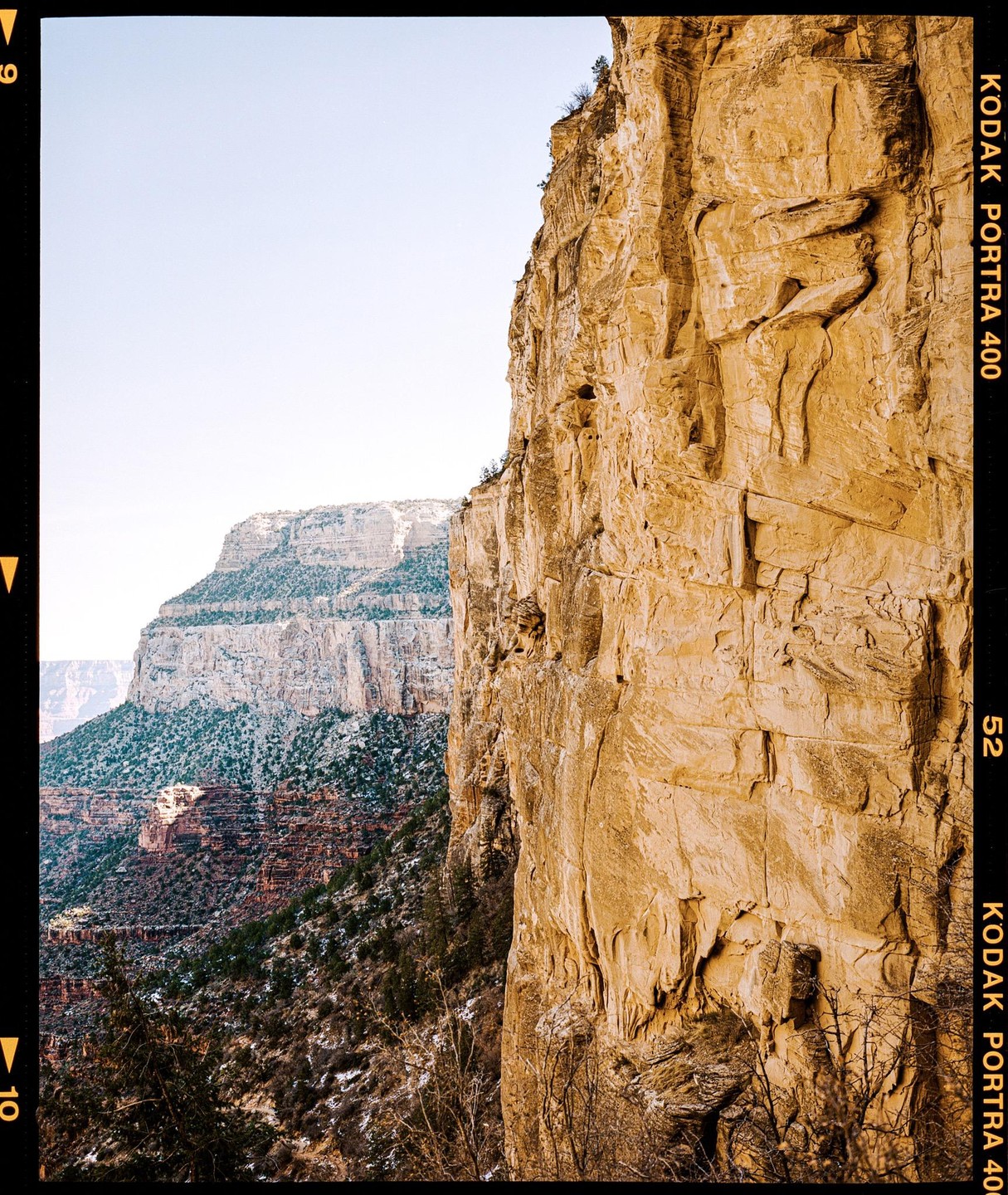 A large rock formation dominates the right side of the frame, with a canyon and mountains visible in the background.