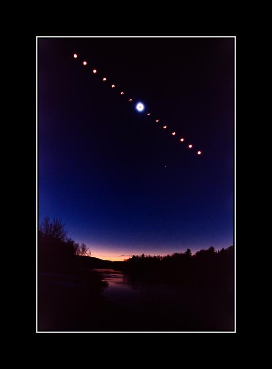 A sequence of solar eclipse phases is visible in the night sky above a river and forest.