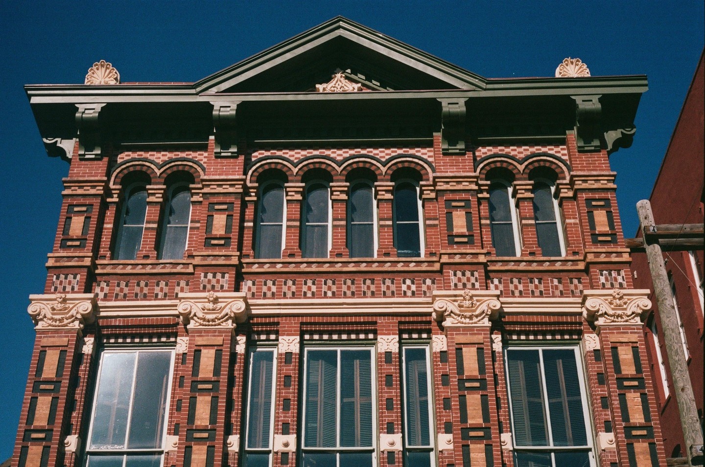 A red brick building with ornate architectural details stands against a clear blue sky.