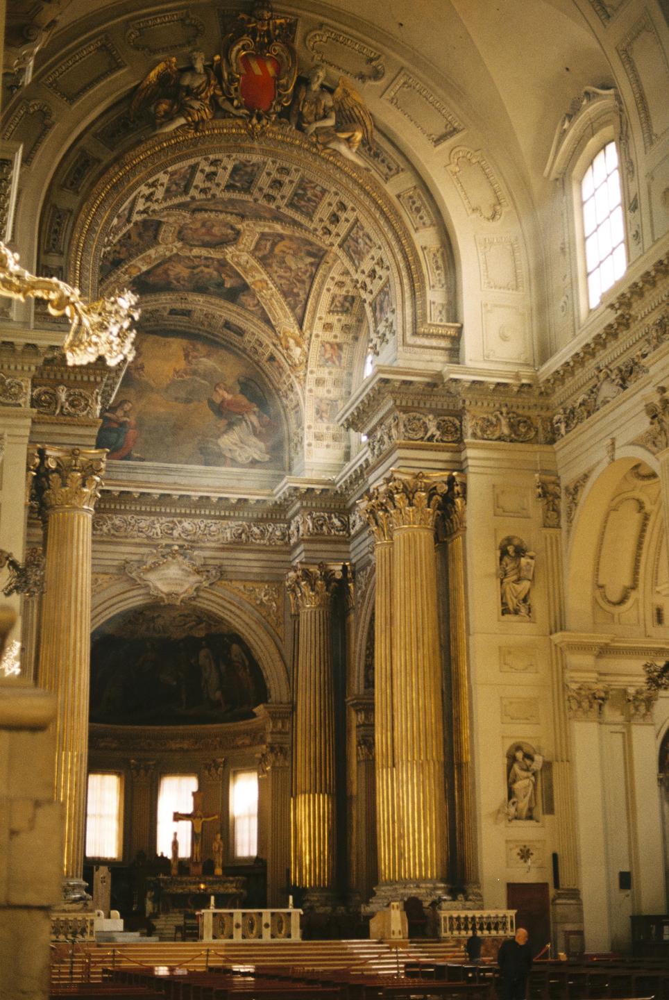 Sunlight illuminates the ornate interior of a church with tall columns and painted ceilings.