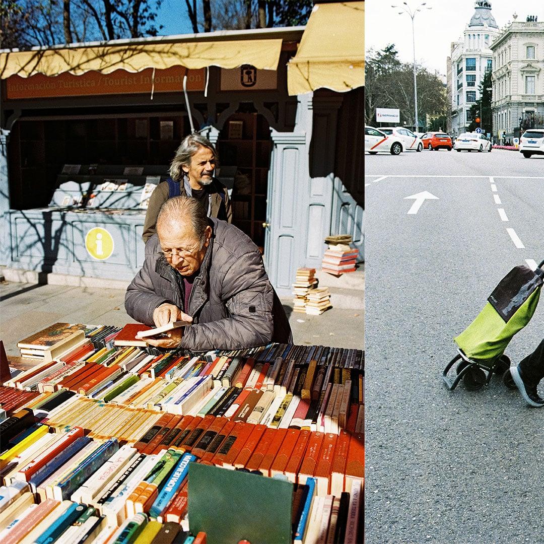 A man in a jacket looks at books on a table in front of a tourist information booth, while another man stands behind him.